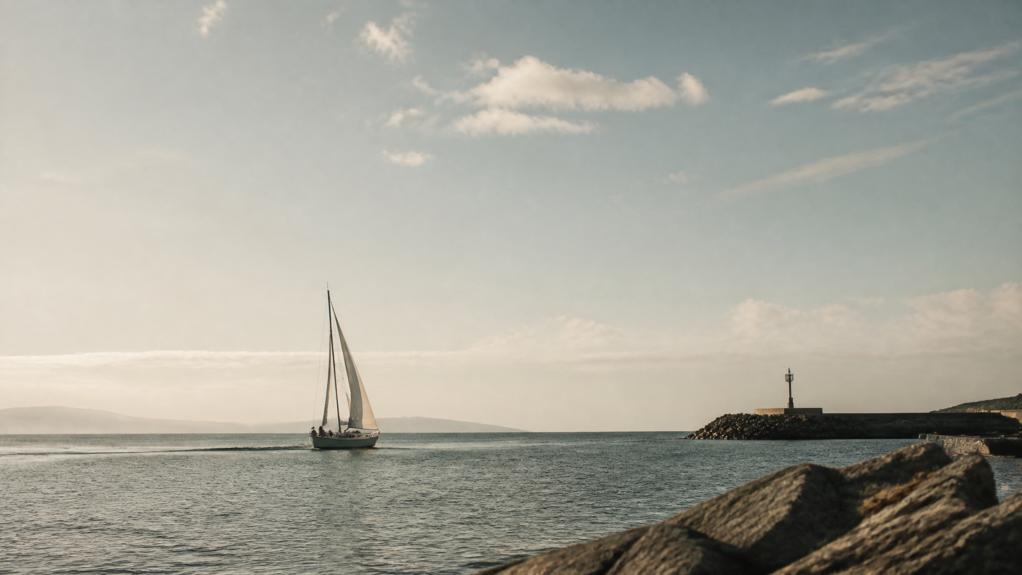 A sailboat catching wind as it leaves a calm harbour